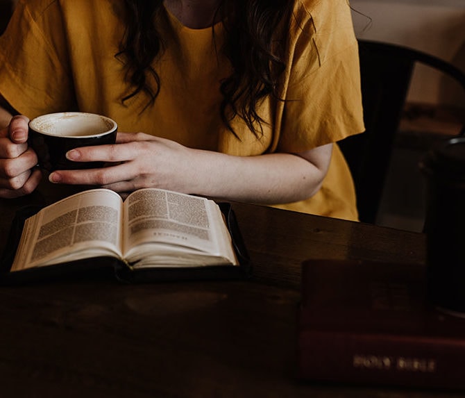 Woman reading the bible with a cup of coffee