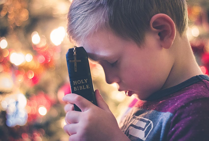 Child holding a bible and praying.